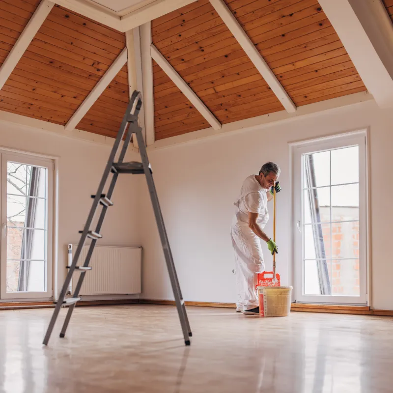 a man dressed in white painting the ceiling of an attic