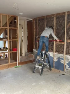 a man on a ladder on a ladder in a room with wood and a red tool box