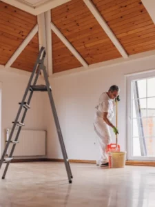 a man dressed in white painting the ceiling of an attic
